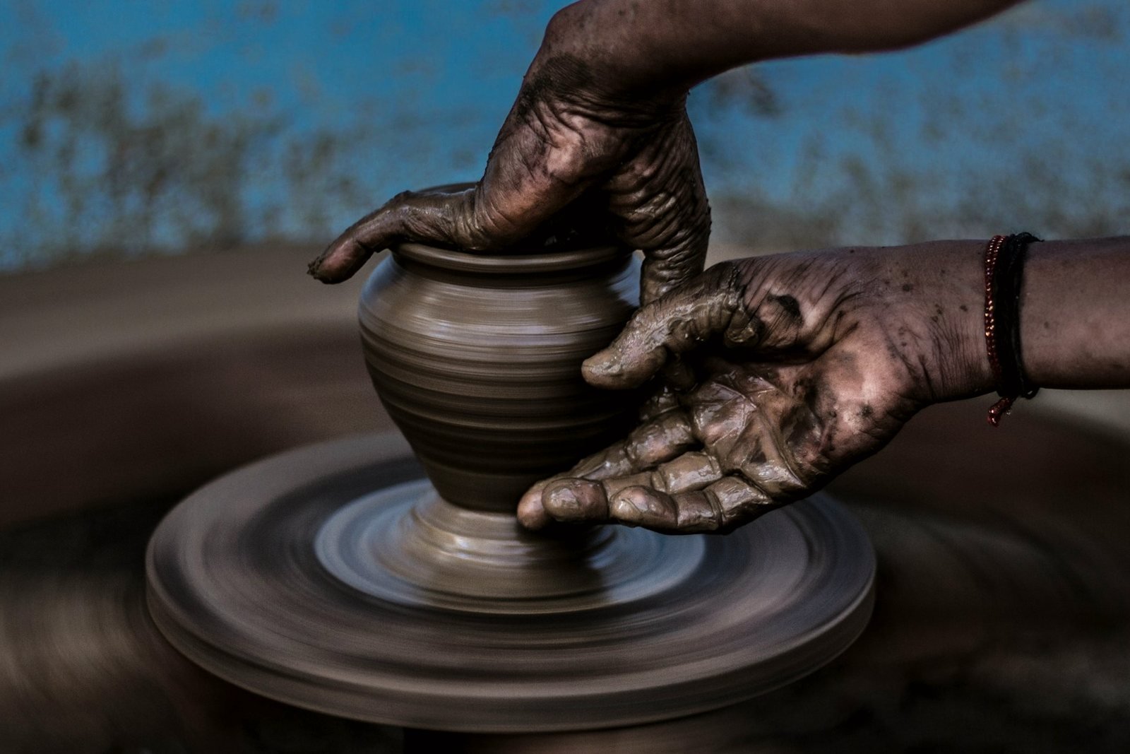 Hands shaping a clay vessel on a pottery wheel