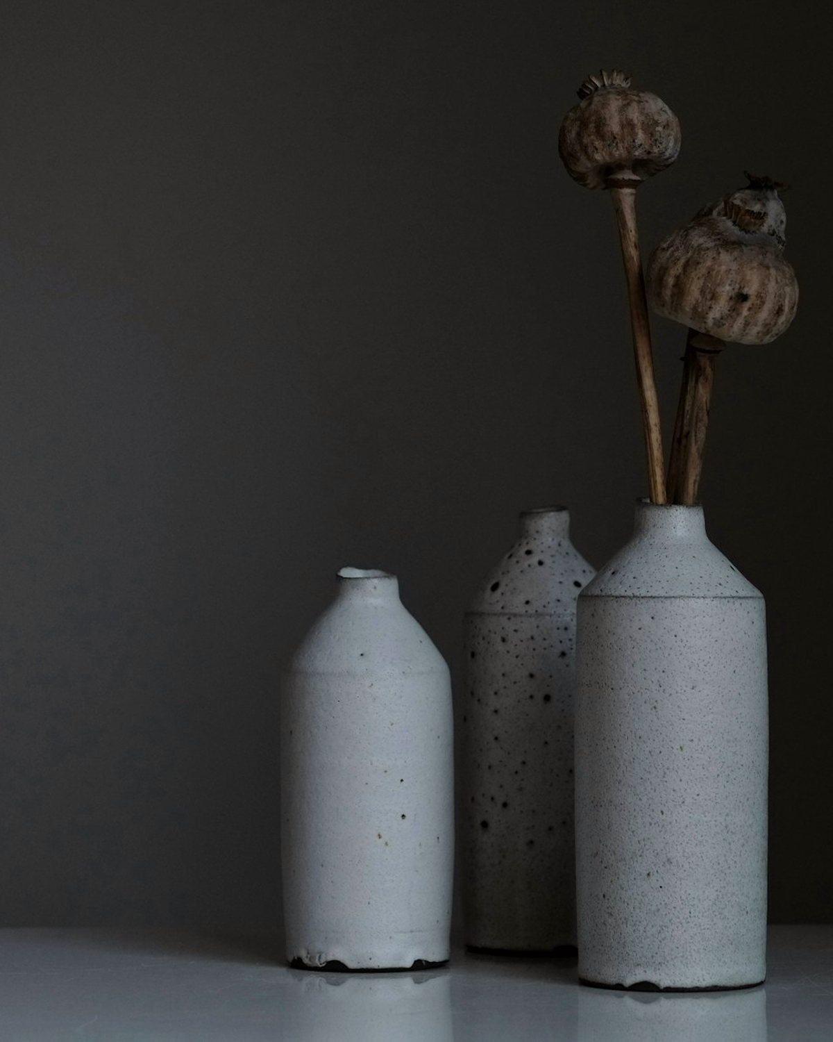 Umbra Vessel Trio in ash-glazed stoneware against a charcoal wall